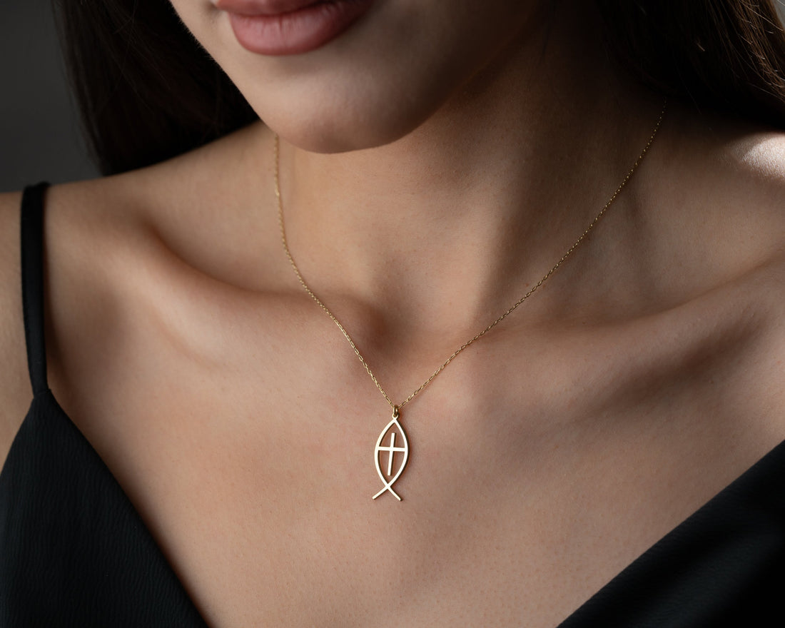 Model wearing a gold Christian fish pendant with a cross inside the outline