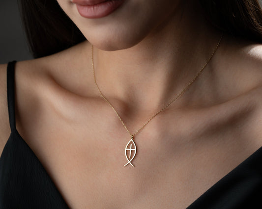 Model wearing a gold Christian fish pendant with a cross inside the outline