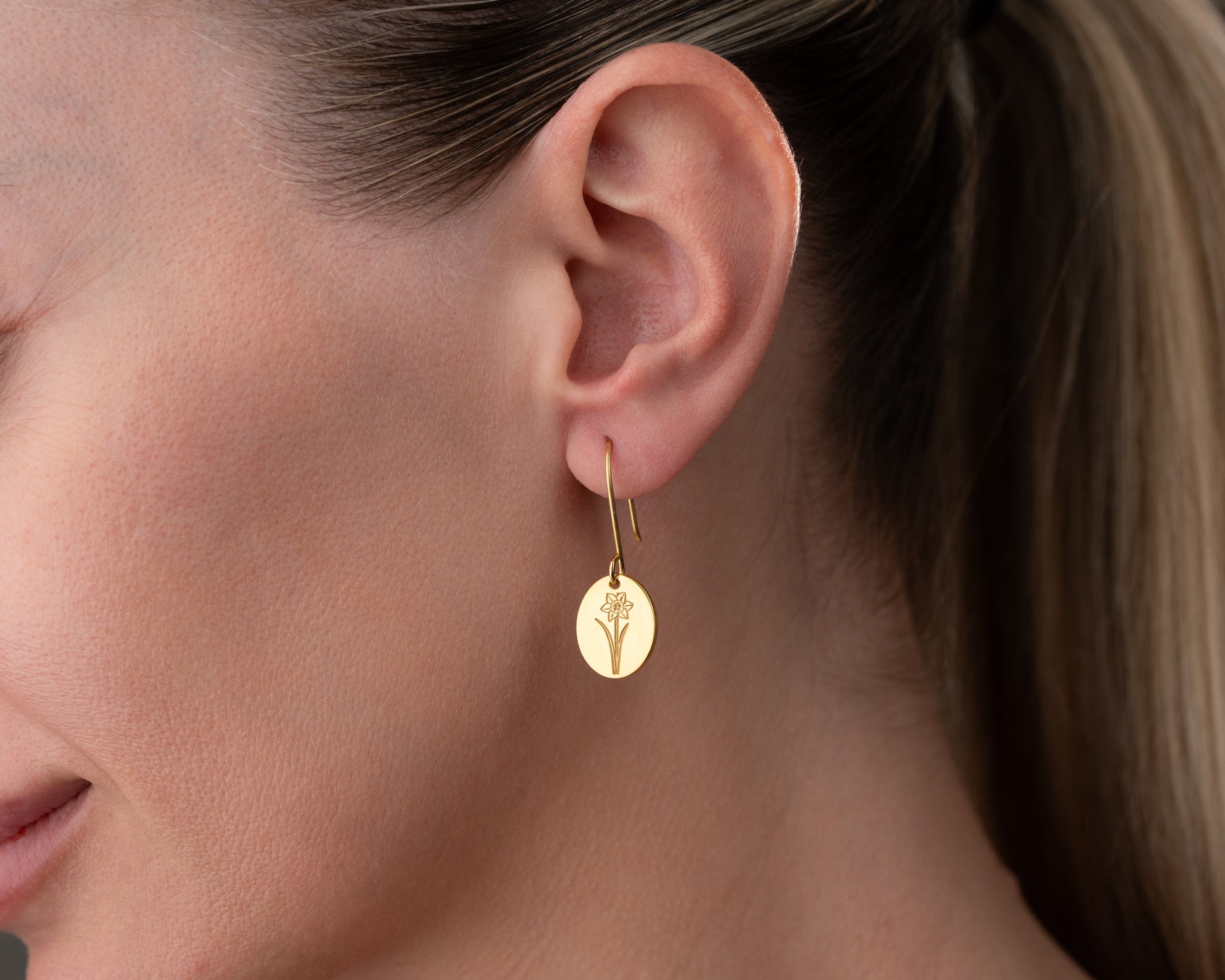 gold birth flower earrings on ear
