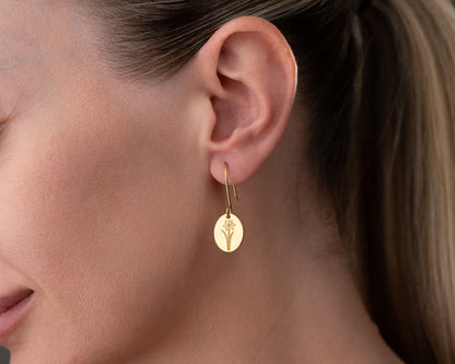 gold birth flower earrings on ear