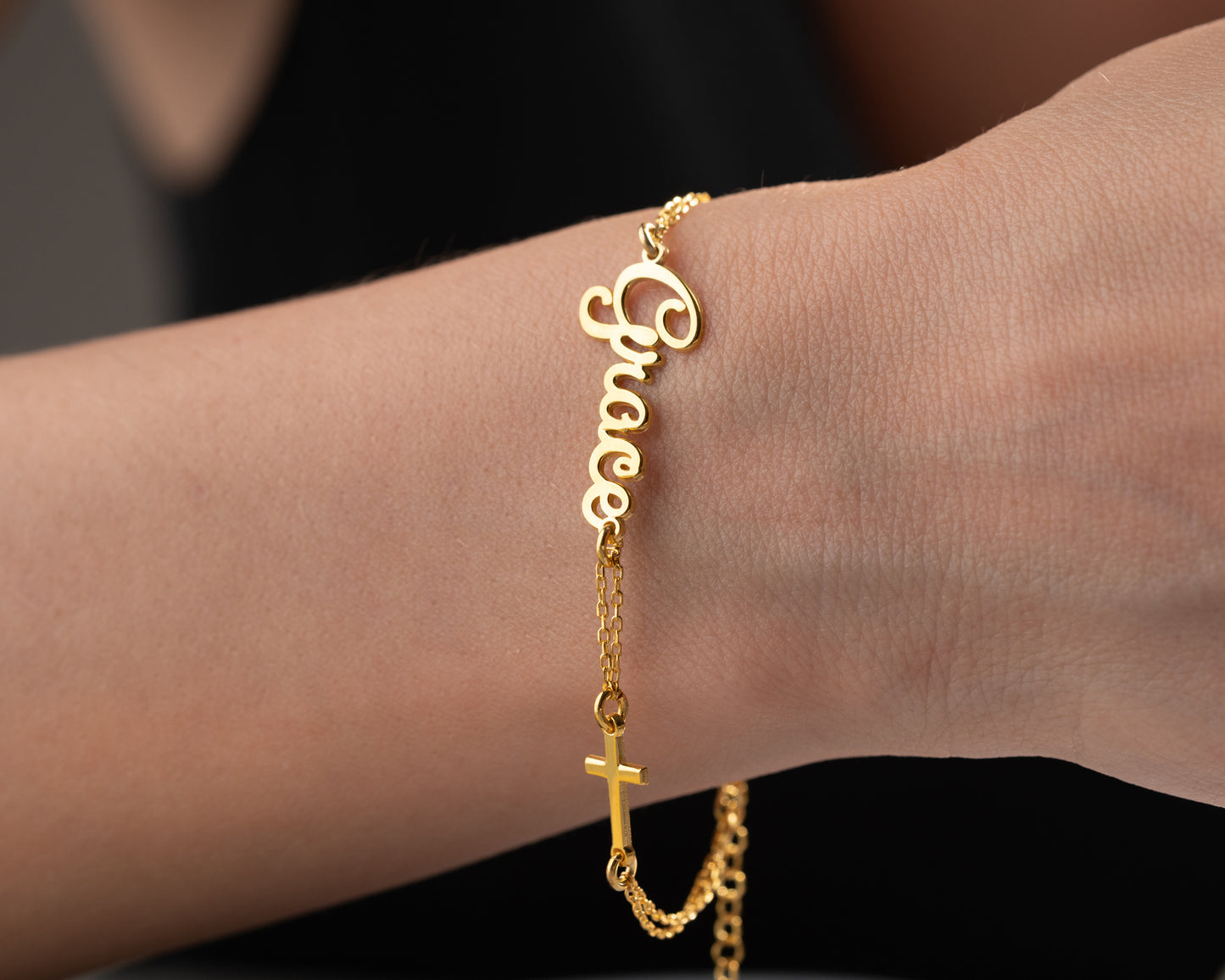 gold cross name bracelet on wrist
